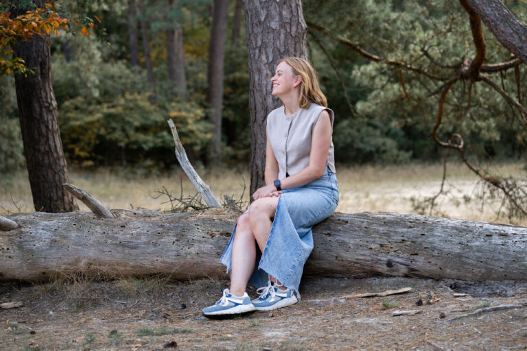 Ingrid Barelds, zittend op een boomstronk in de natuur